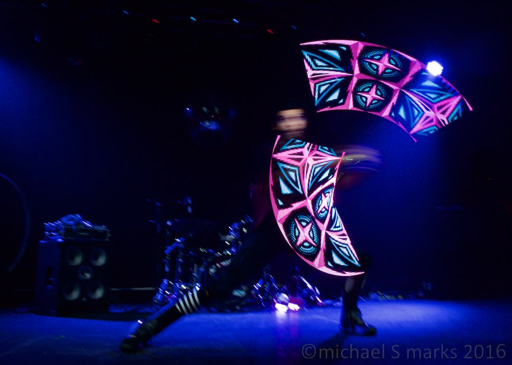 A performer spinning a painted banner under blue stage light